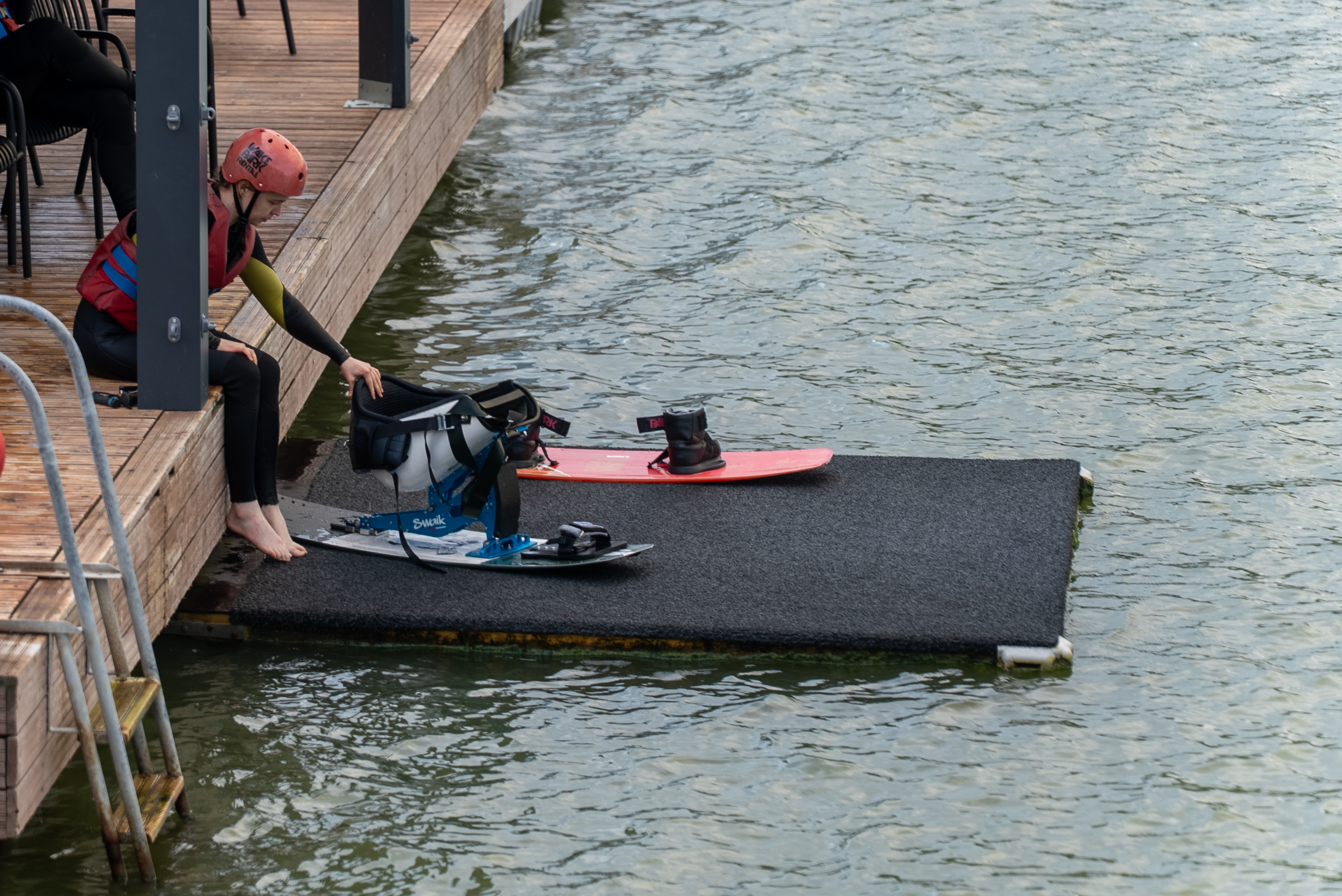 Kuvassa henkilö siirtyy istumaan wakeboardradan lähtöalustalle. 